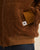 Gros plan sur la poche latérale avec étiquette logo et le poignet élastique de la doudoune camel Côtelé Paris